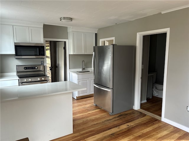 kitchen featuring appliances with stainless steel finishes, light hardwood / wood-style flooring, white cabinets, and sink