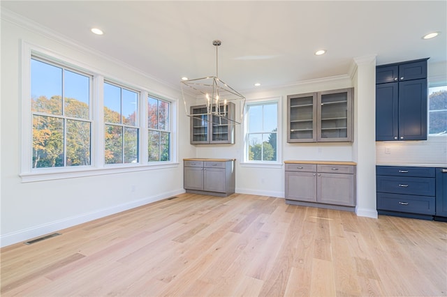 kitchen with decorative backsplash, hanging light fixtures, light wood-type flooring, crown molding, and a notable chandelier