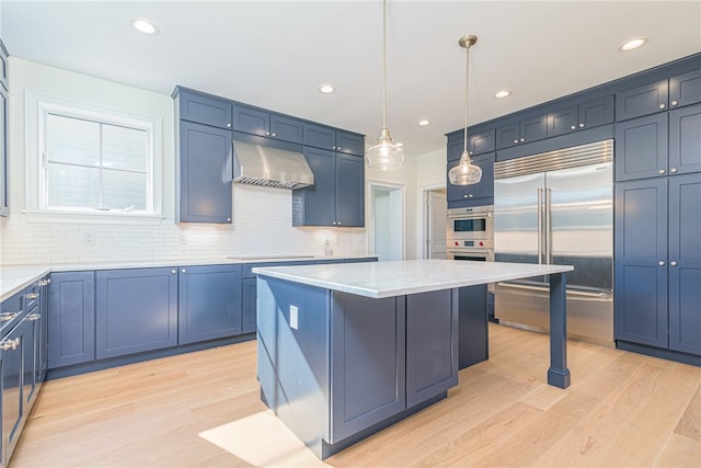 kitchen with a kitchen island, ventilation hood, pendant lighting, blue cabinetry, and appliances with stainless steel finishes