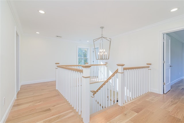 corridor with light hardwood / wood-style flooring, a chandelier, and crown molding