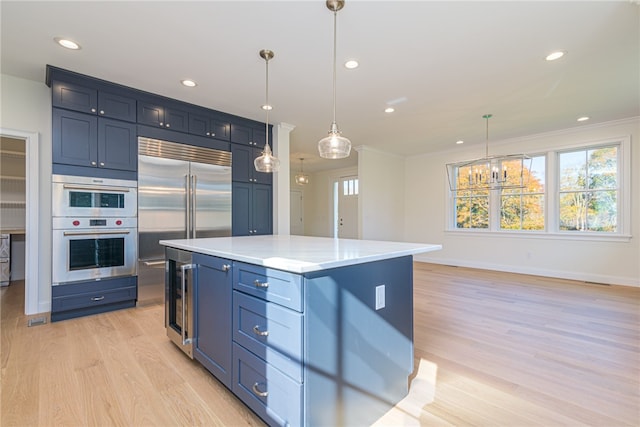 kitchen featuring crown molding, blue cabinetry, stainless steel appliances, and pendant lighting