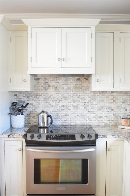 kitchen featuring white cabinets, tasteful backsplash, light stone counters, and stainless steel electric range oven