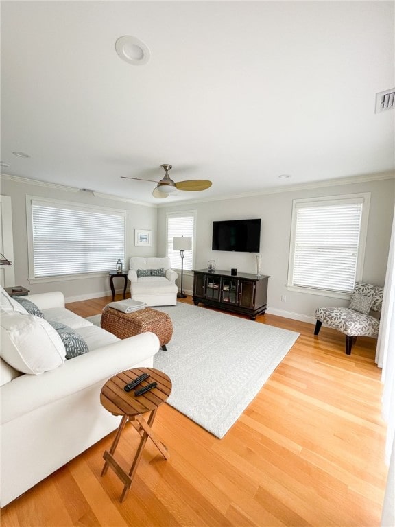 living room featuring ceiling fan, a healthy amount of sunlight, wood-type flooring, and crown molding