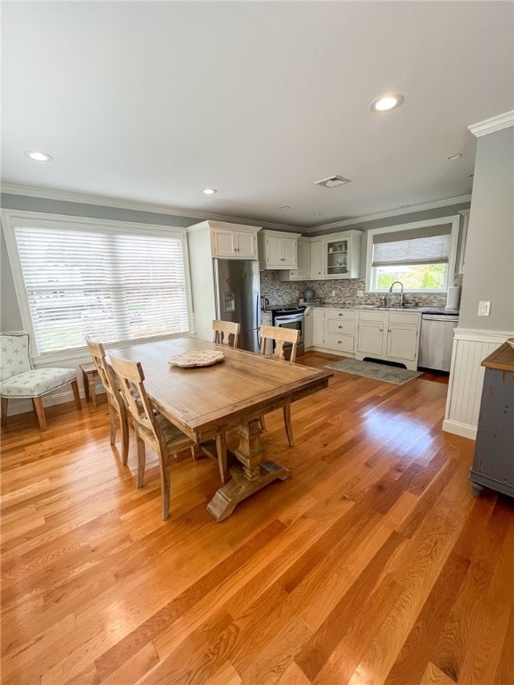 dining area with sink, crown molding, and light hardwood / wood-style flooring