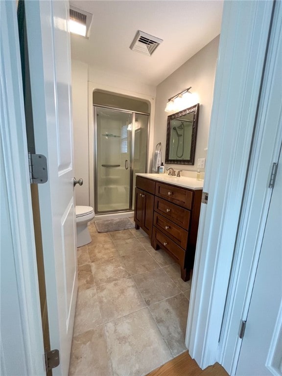 bathroom with vanity, a shower with shower door, and toilet