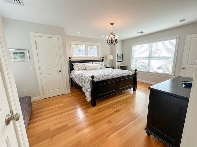 bedroom with an inviting chandelier, multiple windows, and light wood-type flooring