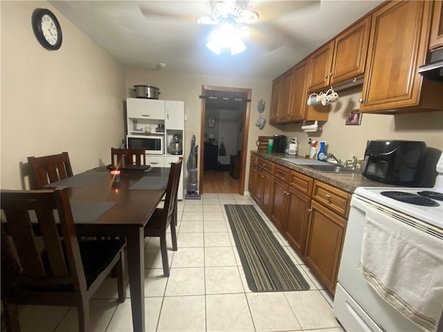 kitchen with white appliances, light tile patterned floors, sink, and ceiling fan