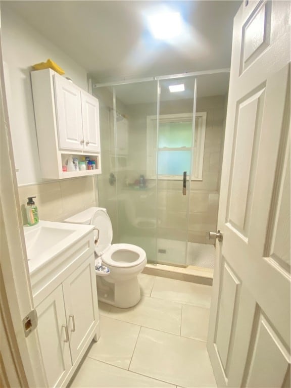 bathroom featuring vanity, toilet, tile patterned floors, and a shower with door