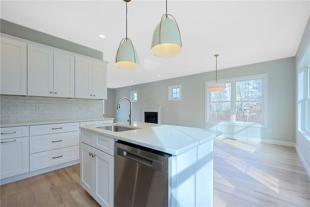 kitchen with sink, white cabinetry, stainless steel dishwasher, and a kitchen island with sink