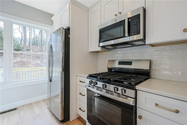 kitchen featuring appliances with stainless steel finishes, light hardwood / wood-style flooring, and white cabinets