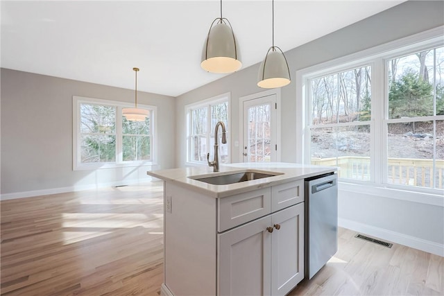 kitchen with pendant lighting, sink, gray cabinets, a kitchen island with sink, and stainless steel dishwasher