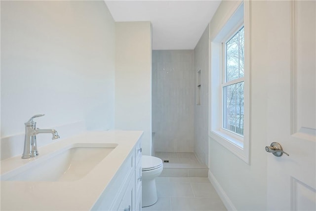 bathroom featuring toilet, tiled shower, plenty of natural light, and vanity