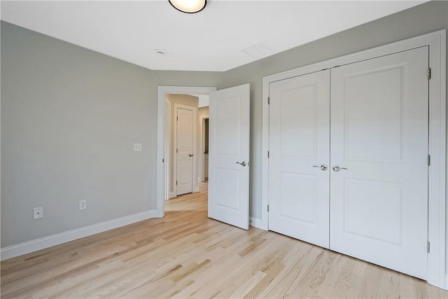 unfurnished bedroom with light wood-type flooring and a closet