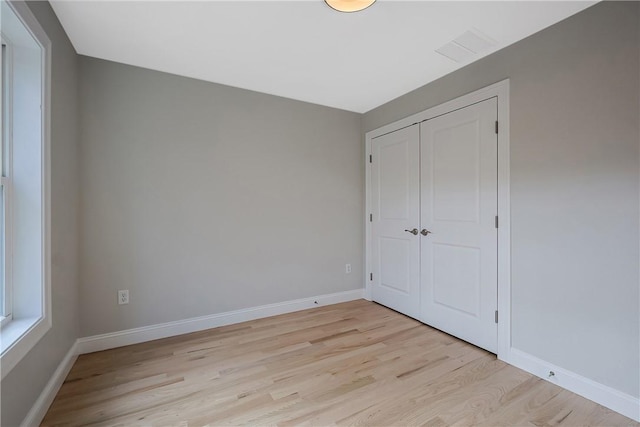 unfurnished bedroom with a closet and light hardwood / wood-style floors