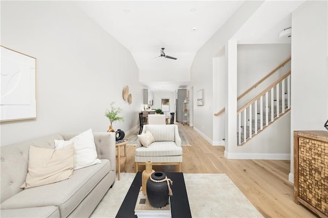 living room featuring ceiling fan, light hardwood / wood-style floors, and vaulted ceiling