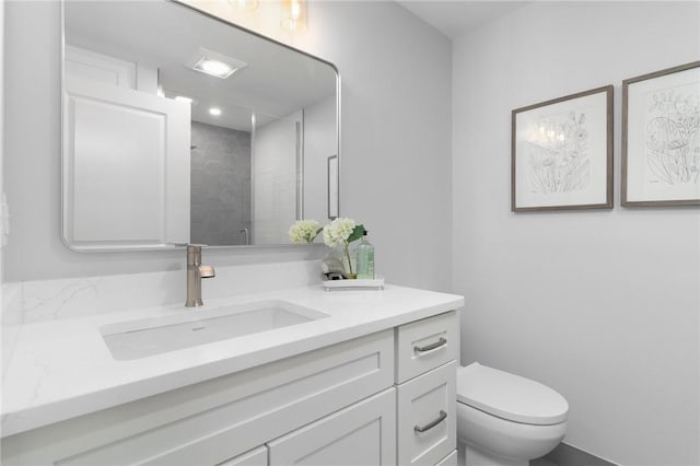 bathroom featuring a tile shower, vanity, and toilet