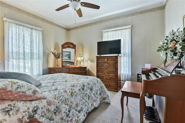 carpeted bedroom featuring ceiling fan, ornamental molding, and multiple windows