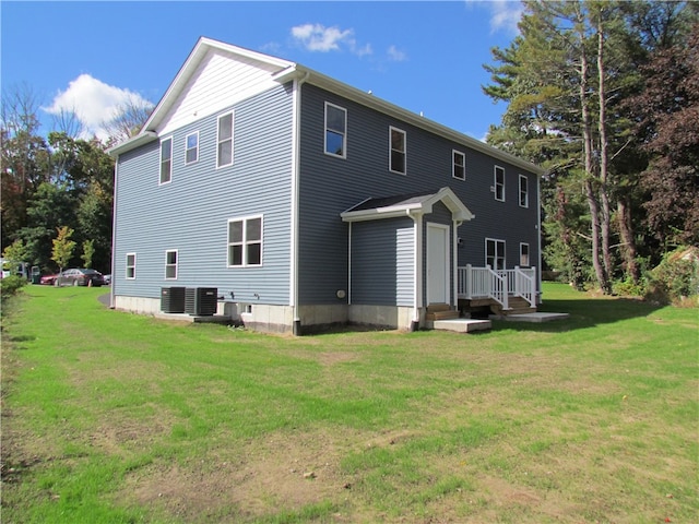 back of house with central AC unit and a lawn