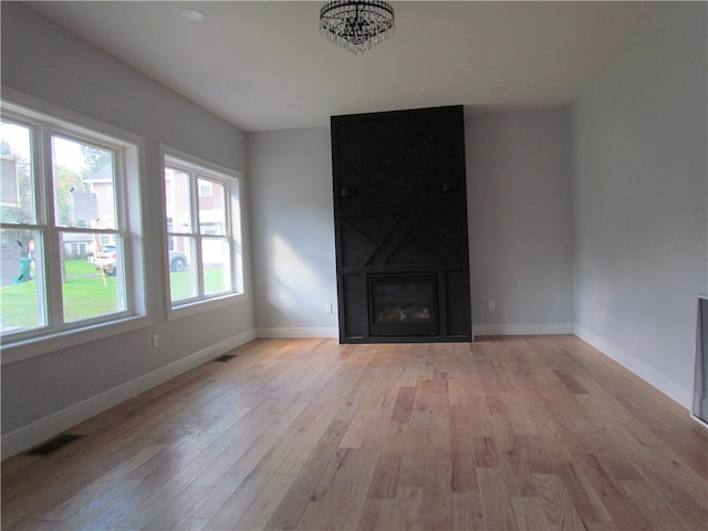 unfurnished living room featuring a wealth of natural light, a fireplace, and light hardwood / wood-style floors