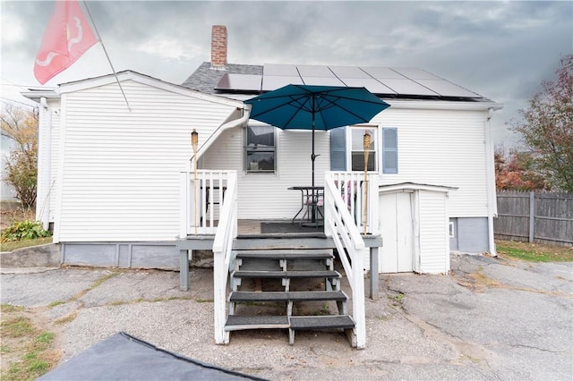 back of property featuring solar panels and a wooden deck