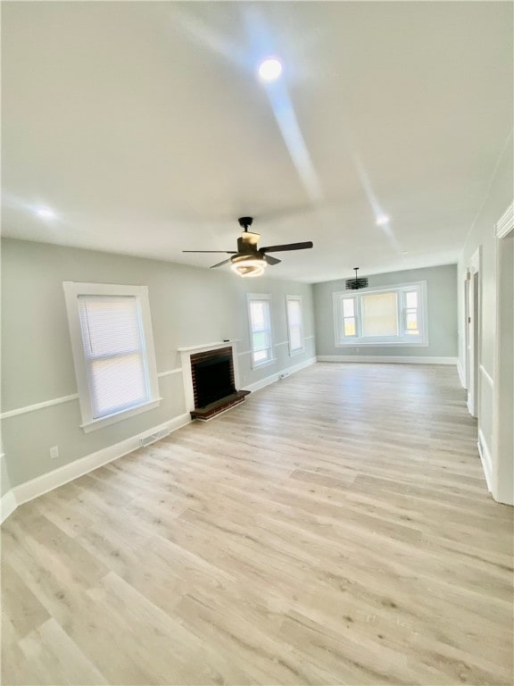 unfurnished living room featuring a fireplace, light hardwood / wood-style flooring, a healthy amount of sunlight, and ceiling fan