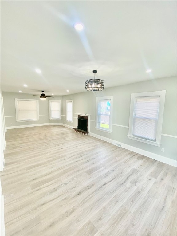 unfurnished living room featuring light hardwood / wood-style floors and ceiling fan with notable chandelier