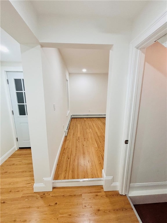 hallway featuring wood-type flooring and a baseboard heating unit