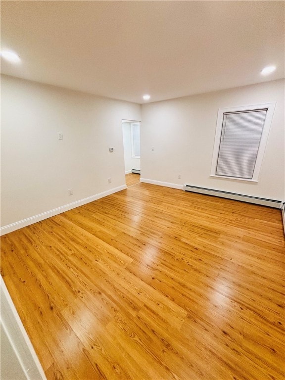 unfurnished room featuring light wood-type flooring and a baseboard heating unit