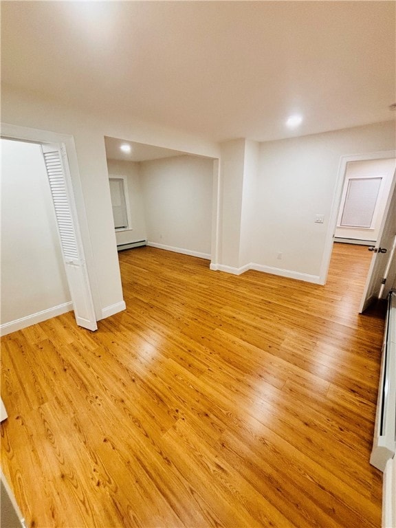 basement with a baseboard radiator and light hardwood / wood-style flooring