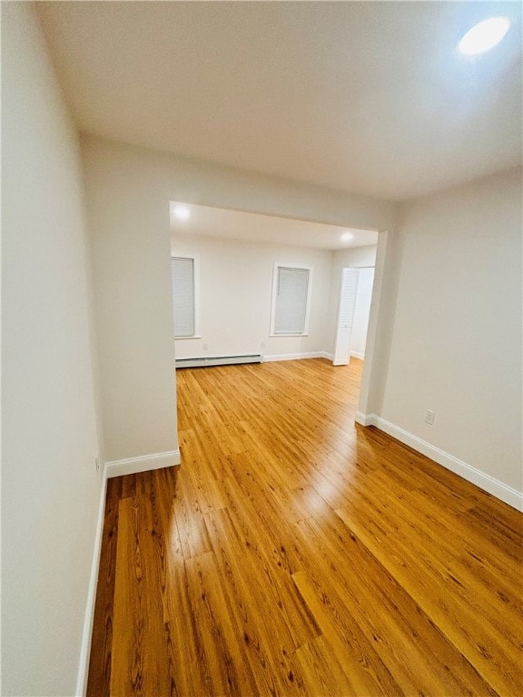 spare room featuring wood-type flooring and a baseboard heating unit