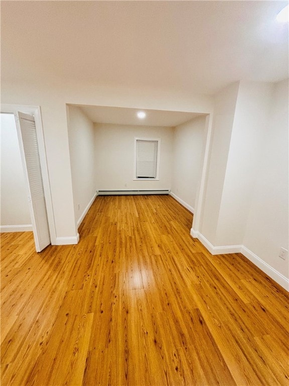 basement featuring light hardwood / wood-style flooring and a baseboard heating unit