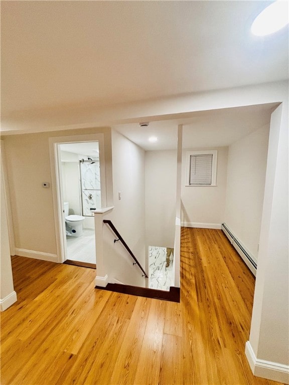 hallway with a baseboard radiator and hardwood / wood-style flooring