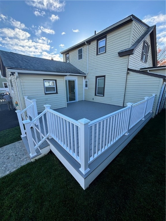 back of house featuring a deck and a lawn