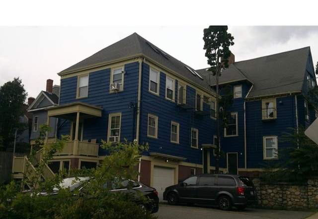 view of front of home featuring a garage, cooling unit, and a balcony