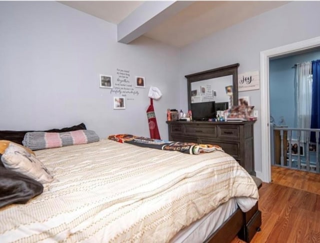 bedroom with beam ceiling and light hardwood / wood-style flooring