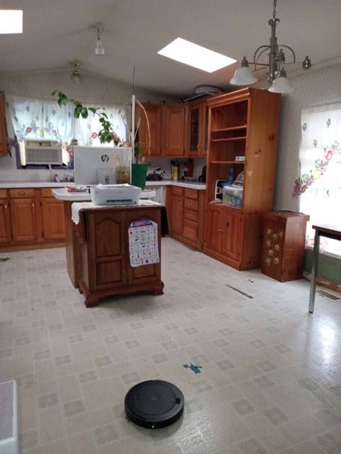 kitchen featuring pendant lighting, lofted ceiling with skylight, a chandelier, and a kitchen island