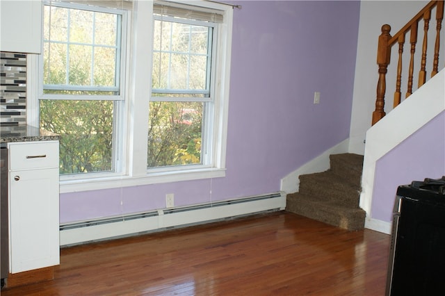 stairway with hardwood / wood-style flooring and baseboard heating