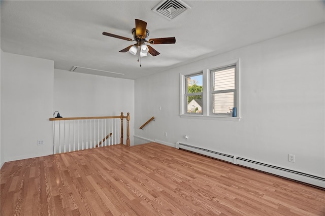 empty room featuring ceiling fan, light wood-type flooring, and a baseboard heating unit