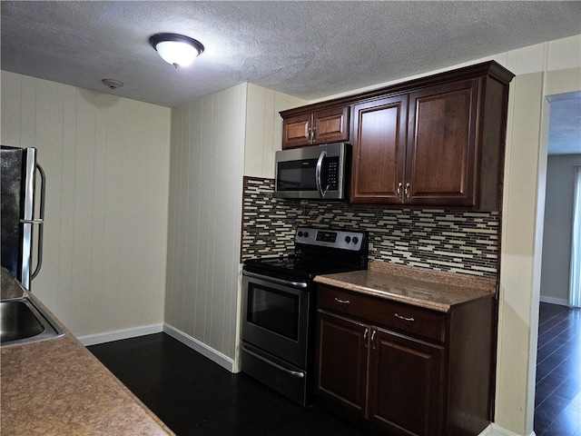 kitchen with stainless steel appliances, wood walls, a textured ceiling, decorative backsplash, and dark brown cabinets