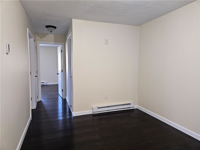 spare room featuring a textured ceiling, dark hardwood / wood-style floors, and baseboard heating