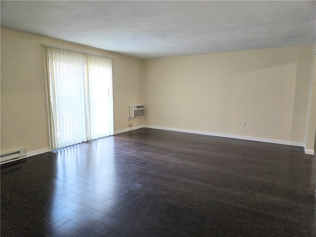 empty room with an AC wall unit, dark wood-type flooring, a textured ceiling, and baseboard heating