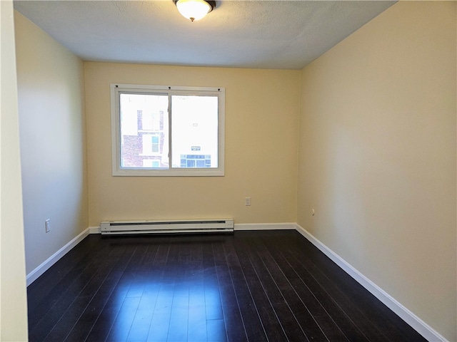 empty room featuring baseboard heating, a textured ceiling, and dark hardwood / wood-style floors