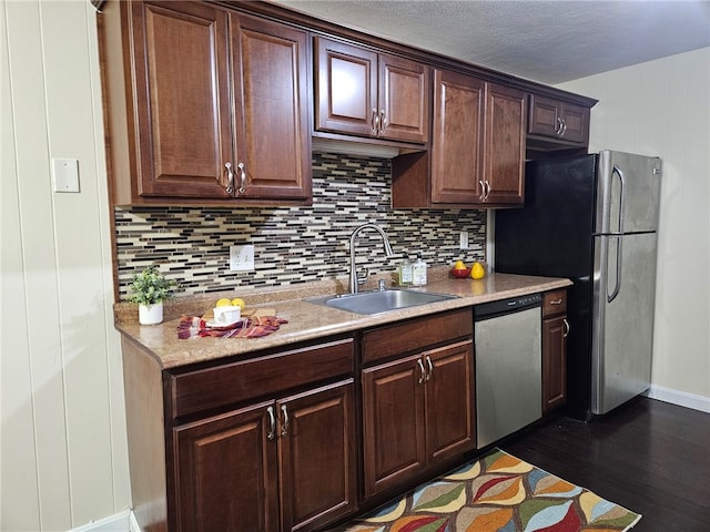 kitchen with dark brown cabinetry, sink, dark wood-type flooring, stainless steel appliances, and backsplash