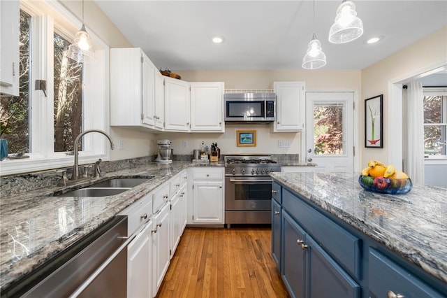 kitchen with stainless steel appliances, white cabinetry, sink, blue cabinetry, and light hardwood / wood-style flooring