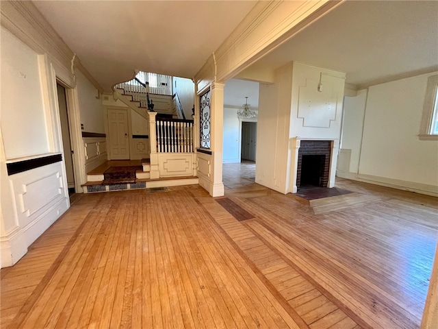 unfurnished living room featuring light wood-type flooring, a fireplace, and crown molding