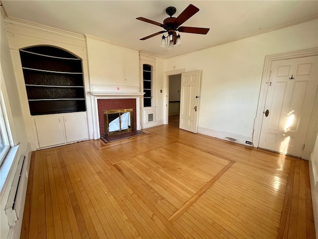 unfurnished living room featuring built in shelves, a fireplace, wood-type flooring, and a baseboard heating unit