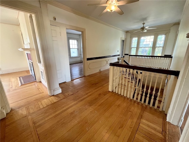 hall with light hardwood / wood-style flooring, ornamental molding, and plenty of natural light