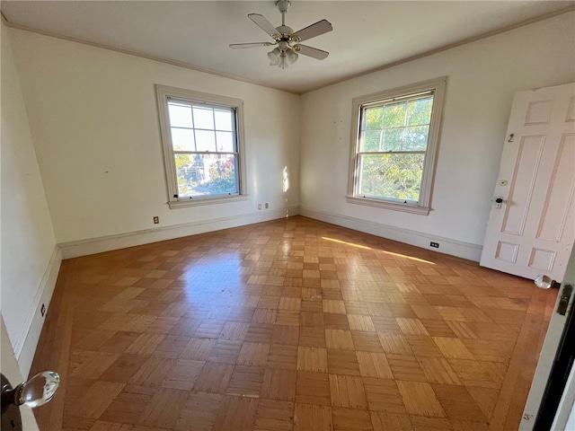 spare room with a wealth of natural light, ceiling fan, and light parquet floors