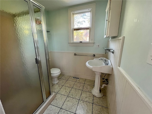 bathroom featuring toilet, tile patterned flooring, and a shower with shower door