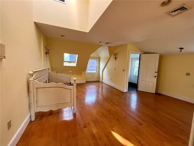 bonus room with hardwood / wood-style floors and lofted ceiling with skylight